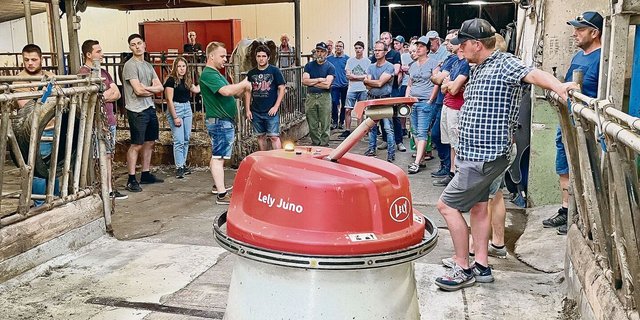Der automatische Futterschieber «Wäutu» lässt sich von den Besuchenden auf dem Sonnhaldenhof nicht stören, während Betriebsleiter Marc Grüter (im grünen T-Shirt) erklärt.