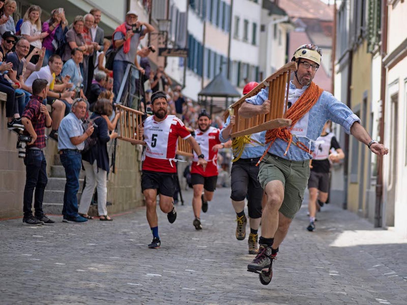 Die Läufer mit den über 8 Meter langen Chriesileitern kurz vor der ersten Kurve, anlässlich des Zuger Chriesisturms 2018. (Bilder zVg)