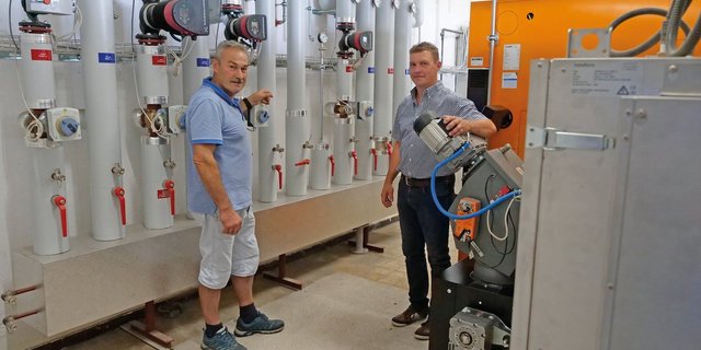 Landwirt Urs Steinmann (links) und Andreas Lüthi von der Schmid AG im Heizraum mit der neuen Hackschnitzel-Heizung und dem Wärmeverteilnetz. Bild: Beat Schmid