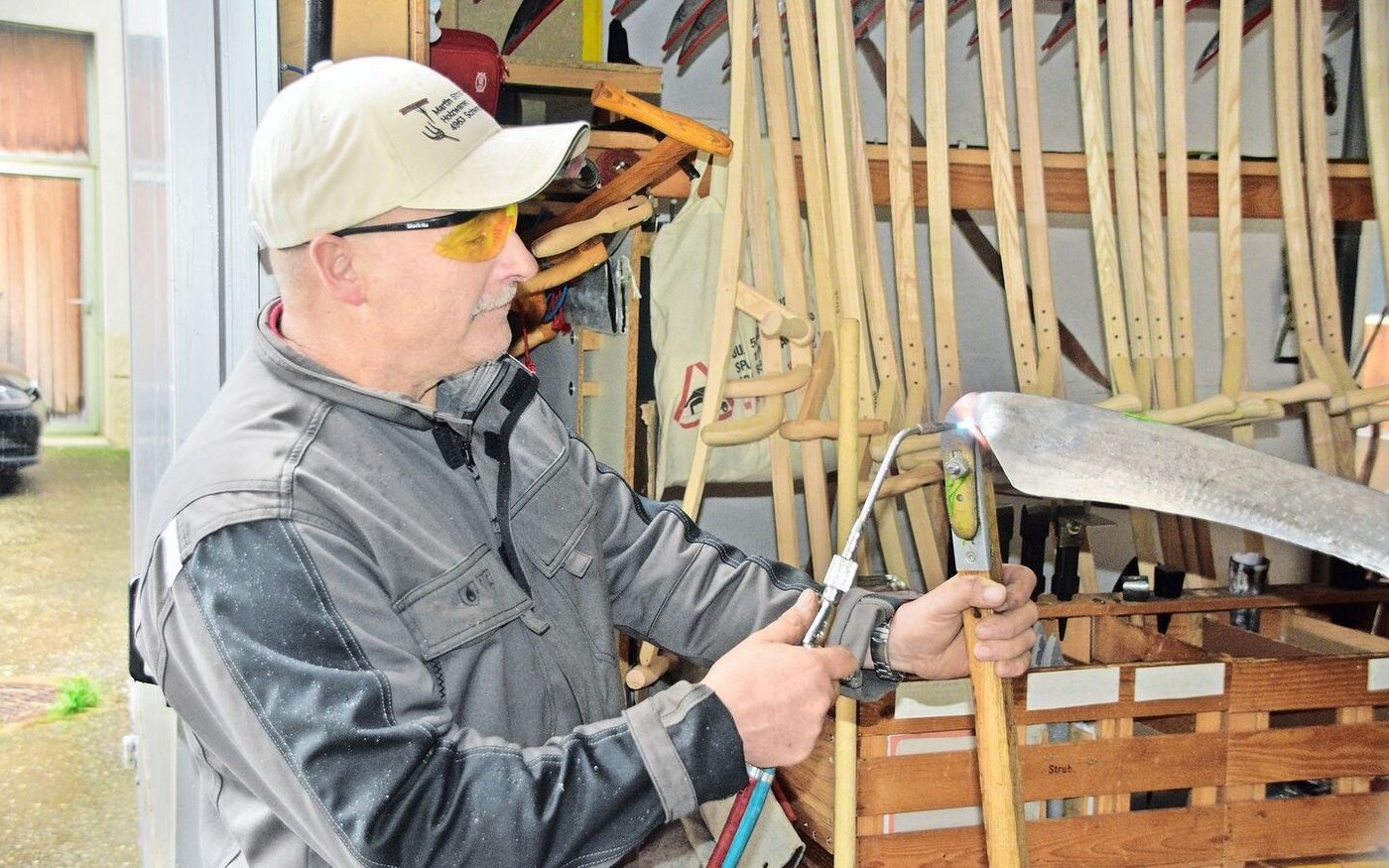 Der Kursleiter Martin Strub korrigiert hier mit Wärme den Zaum eines Sensenblattes, damit er es richten kann.   