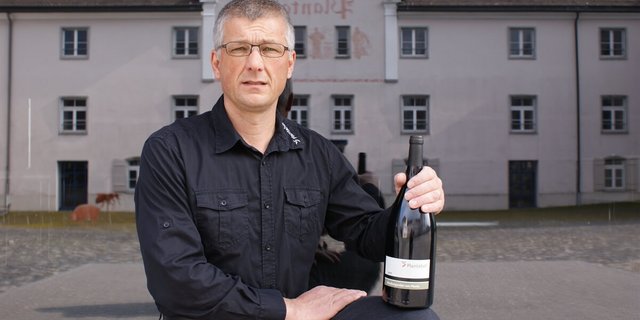 Der Rebmeister Moritz Villiger posiert mit dem Bündner Regierungswein, der künftig ebenfalls am Plantahof in Bioqualität produziert werden wird. (Bild zVg)