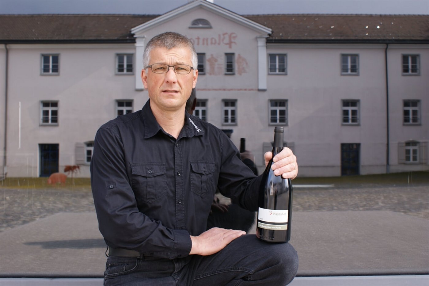 Der Rebmeister Moritz Villiger posiert mit dem Bündner Regierungswein, der künftig ebenfalls am Plantahof in Bioqualität produziert werden wird. (Bild zVg)