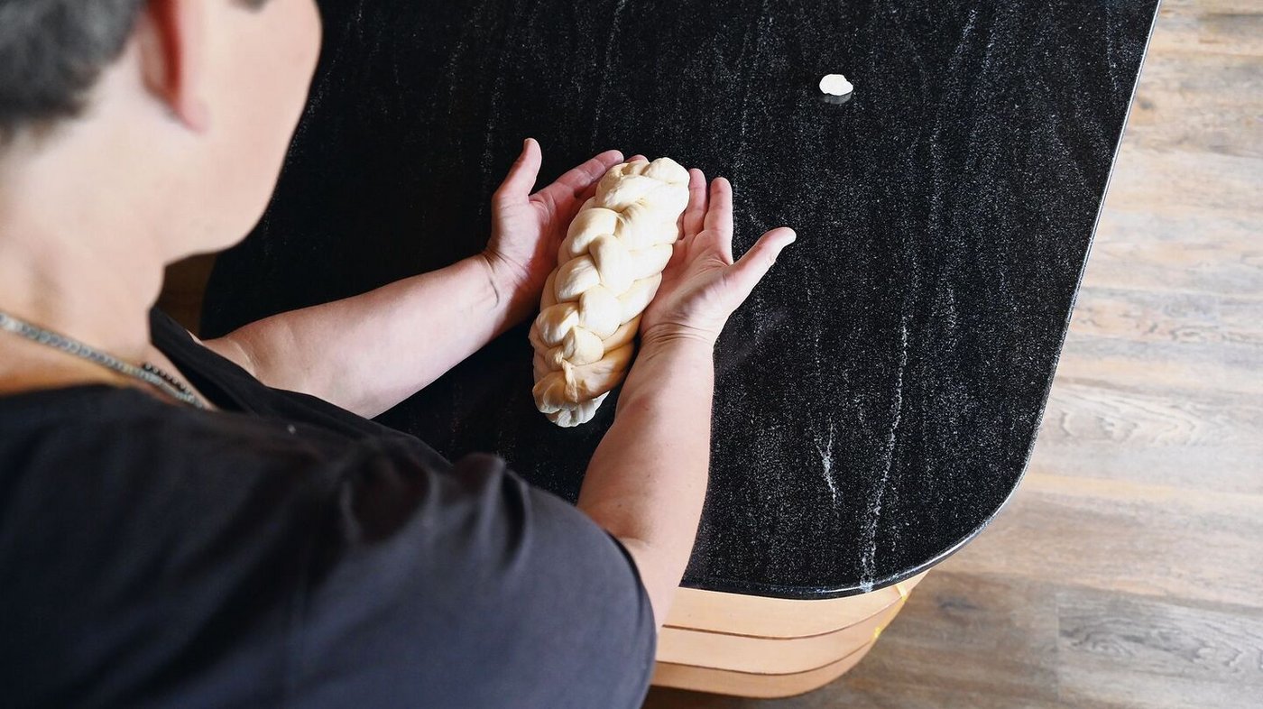 Mit den Handkanten unter den Zopf greifen, etwas gegen oben drücken und Form geben. 