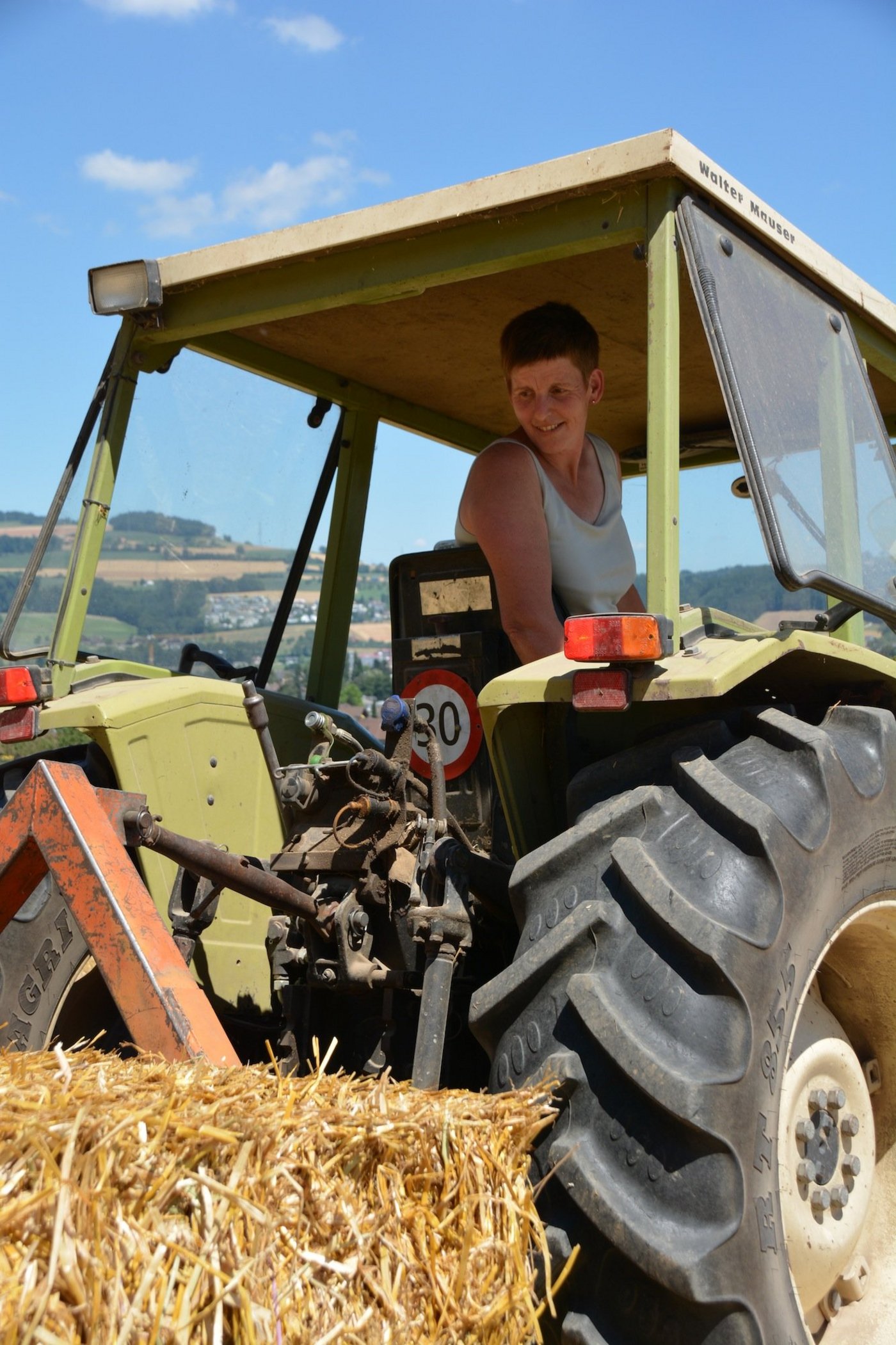 Bäuerin Ursi Troxler aus Mauensee führt auf dem Stoppelfeld Quaderballen zusammen. (Bild aem)