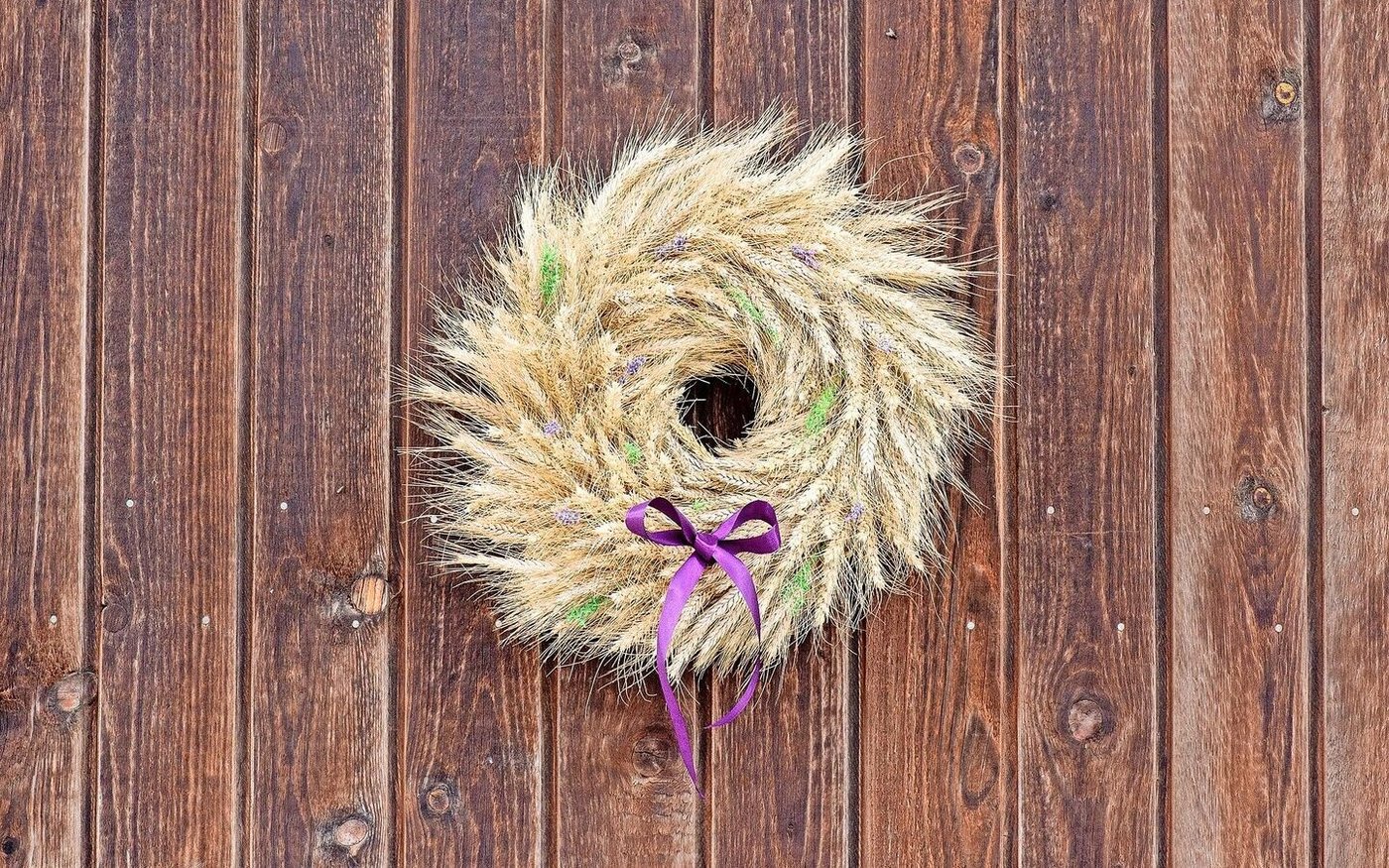 Der Getreidekranz macht sich wunderbar an einer Scheunenwand als Sommerliche Dekoration.