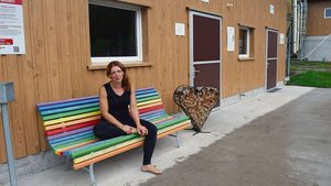 Beate Städler vor de Beate Städler vor dem Hühnerstall, wo Kunden Eier in Selbstbedienung kaufen können. Die farbenfrohe Bank und die Herz-Dekoration verkörpern ein Stück weit ihren Charakter.