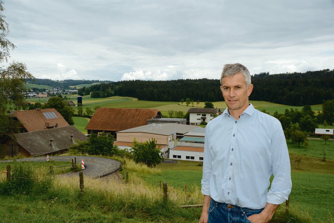 Die Bauphase ist abgeschlossen: Franzsepp Erni mit  Hofgruppe im Hintergrund. Der Stall für die 100 Muttersauen ist zweistöckig und wirkt kompakt. (Bilder Armin Emmenegger)