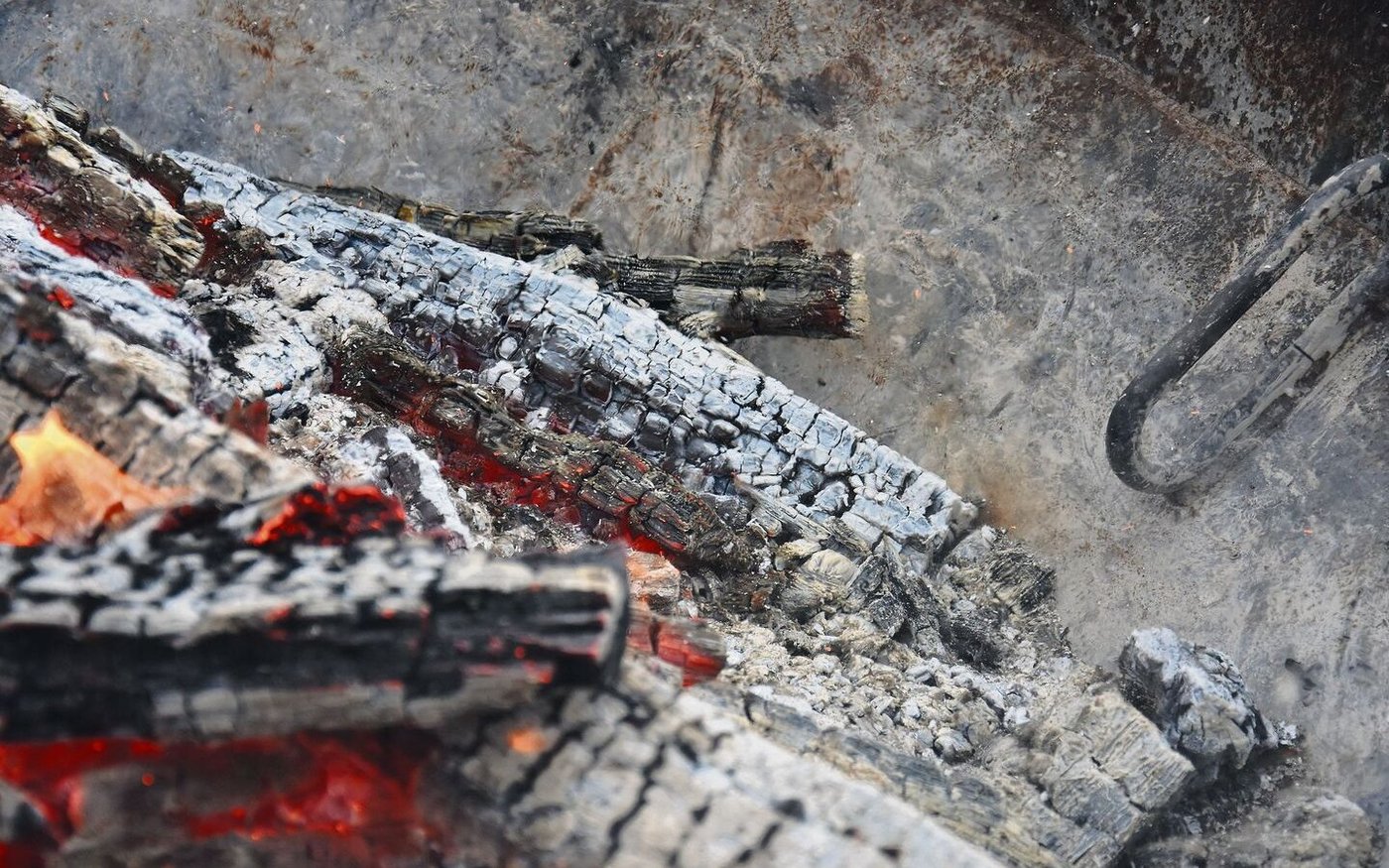 Pflanzenkohle (hier die Herstellung in einem Kon-Tiki) hat eine grosse Oberfläche, um Stoffe zu binden. 