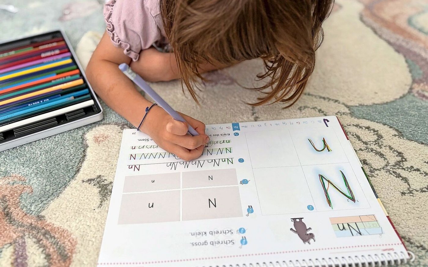 Auf dem Teppich statt am Tisch: Martina Brühlmann plädiert dazu, das Kind den Ort für die Hausaufgaben selbst wählen zu lassen. Wenn es lieber liegt oder steht, warum nicht? Sitzen muss es in der Schule schon viel. 