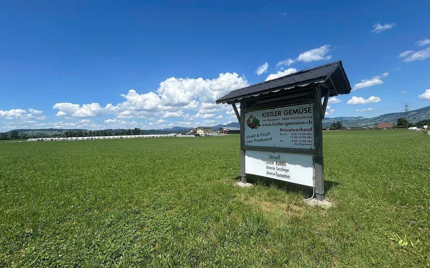 Der Betrieb in der Linthebene ist mit der Beschilderung gut zu finden. Im Hintergrund sind die Gemüsetunnels und Betriebsgebäude zu sehen.
