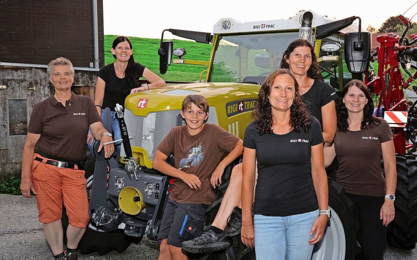 Die Inhaberinnen des Familienunternehmens Sepp Knüsel AG mit Nachwuchs umringen einen heugelben Rigitrac Model SKH 75. 