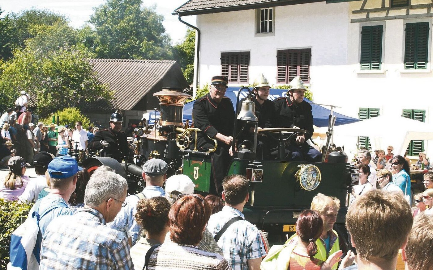 Unzählige Besucher(innen) säumen den Strassenrand während des Corsos: Ein altes Feuerwehrmobil fährt vorbei.