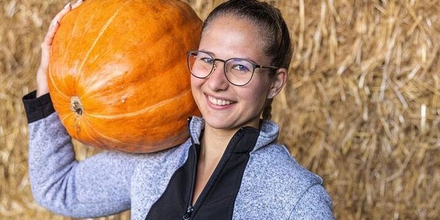 Faye Kleiner schultert einen Kürbis.