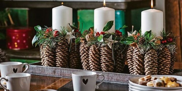 Natürlich und festlich: Kerzenhalter aus Fichtenzapfen. Die Kerzen werden mit Wachsplättchen festgeklebt.