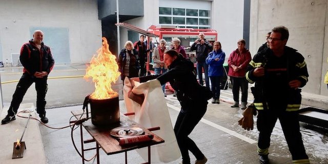 Eine Gruppe Bäuerinnen übt das Löschen eines Fritteusenbrands mit der Löschdecke: Die Decke darf nicht von oben über die Fritteuse gestülpt werden, sondern muss über den Fritteusenrand geschoben werden. (Bilder und Video Esther Thalmann)