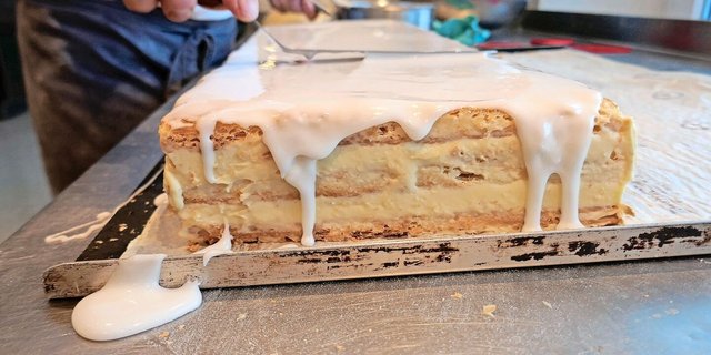 Das Auftragen der obersten Schicht, des Fondants. Es braucht auch hier Sorgfalt, damit keine «Teigbrösmeli» die glatte Glasur zerstören.