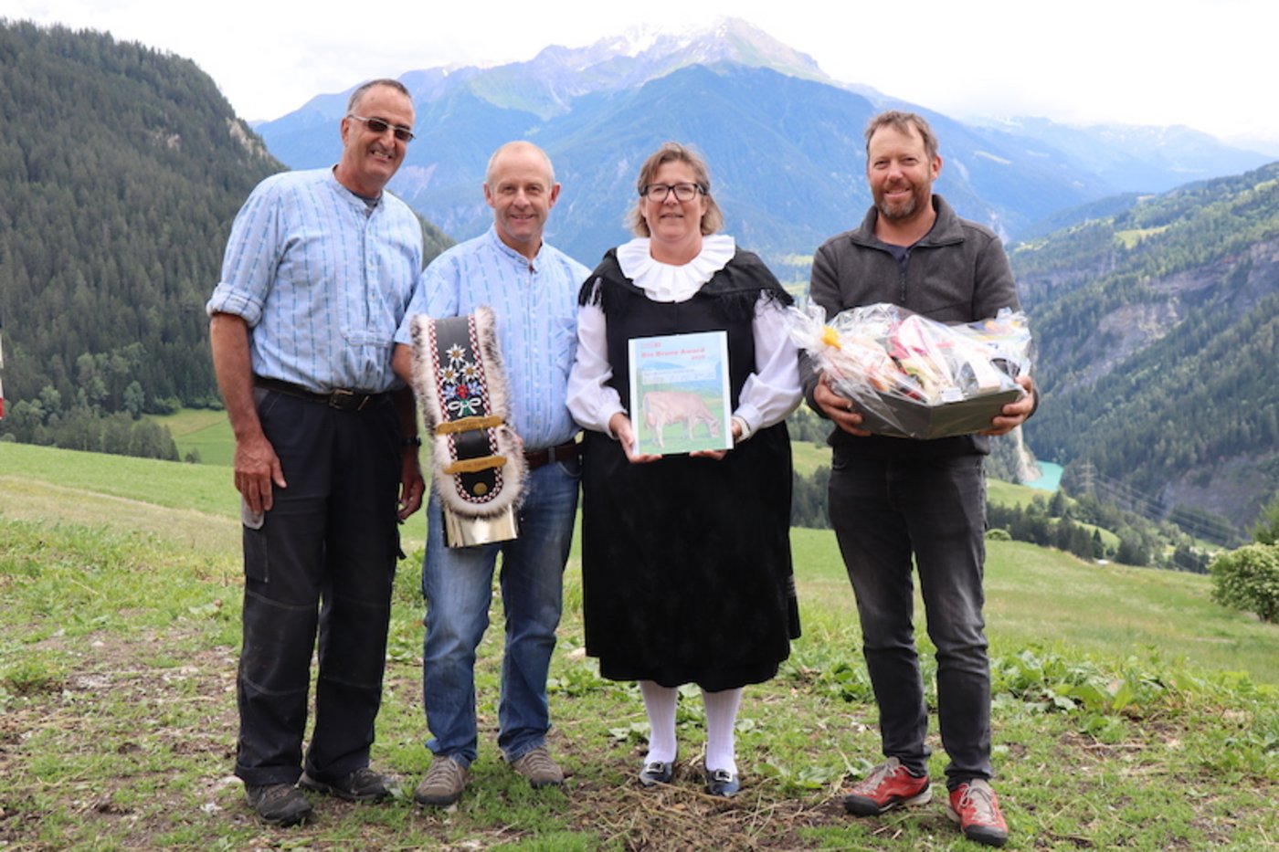 Als Anerkennung ihrer Leistung wurden Toni (mit Glocke) und Nicole Sigron (mit Bio Bruna Award) von Marco Parpan (l.) Lucas Margreth (r.) mit einem Früchtekorb beschenkt. (Bild vcd)
