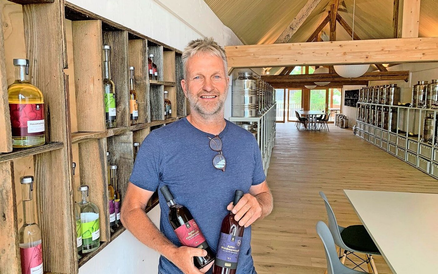 Urs Amrein mit einem Apfel-Kirschensaft im neuen Lagerraum, wo in Stahltanks auch die vielen Edeldestillate gelagert werden. 